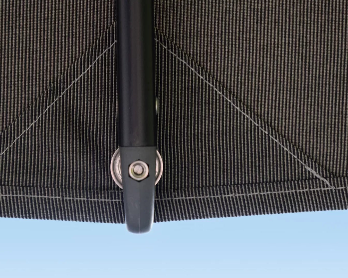 Close-up of a black umbrella handle with a blue sky background