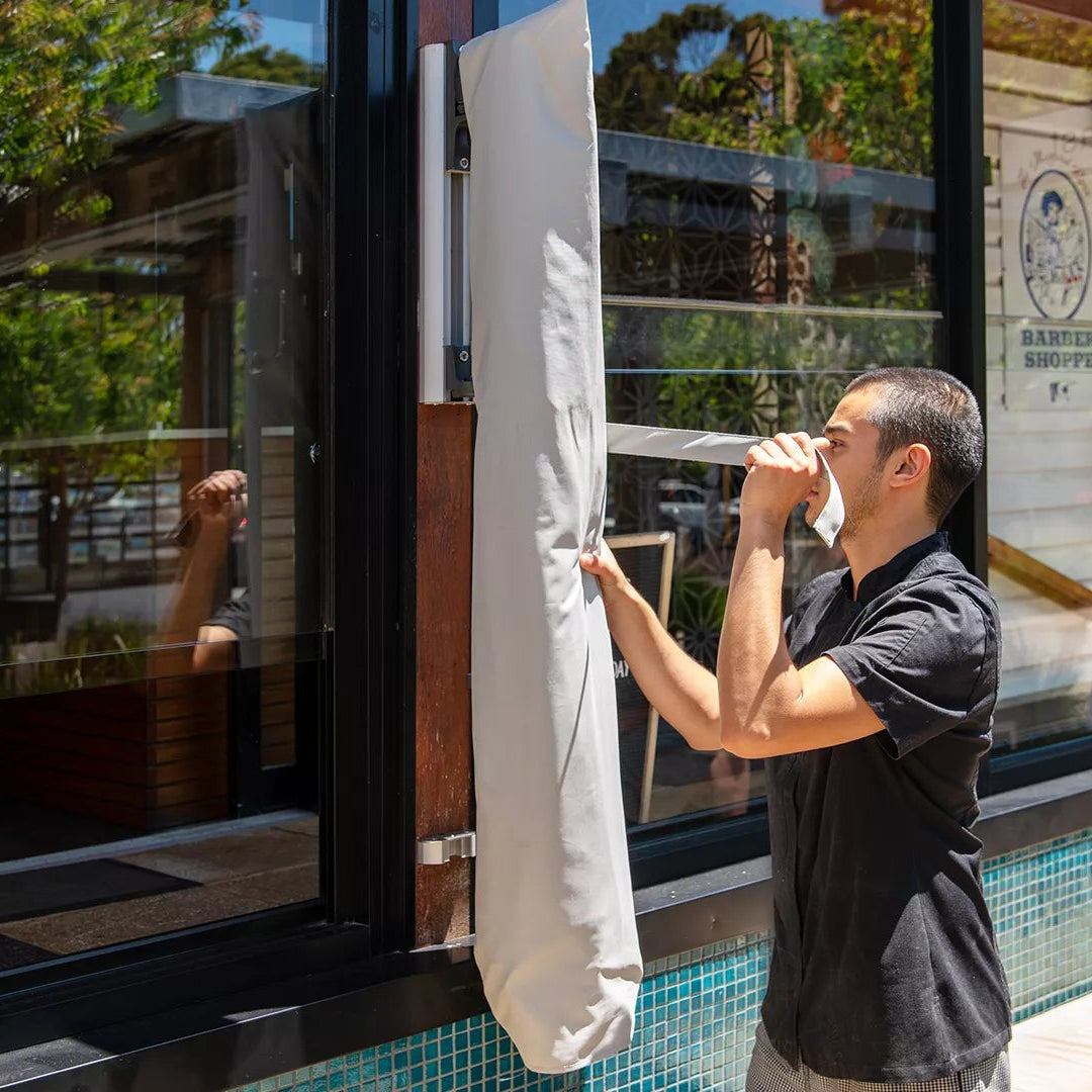 Person tying a white wall mounted umbrella cover in of a cafe window