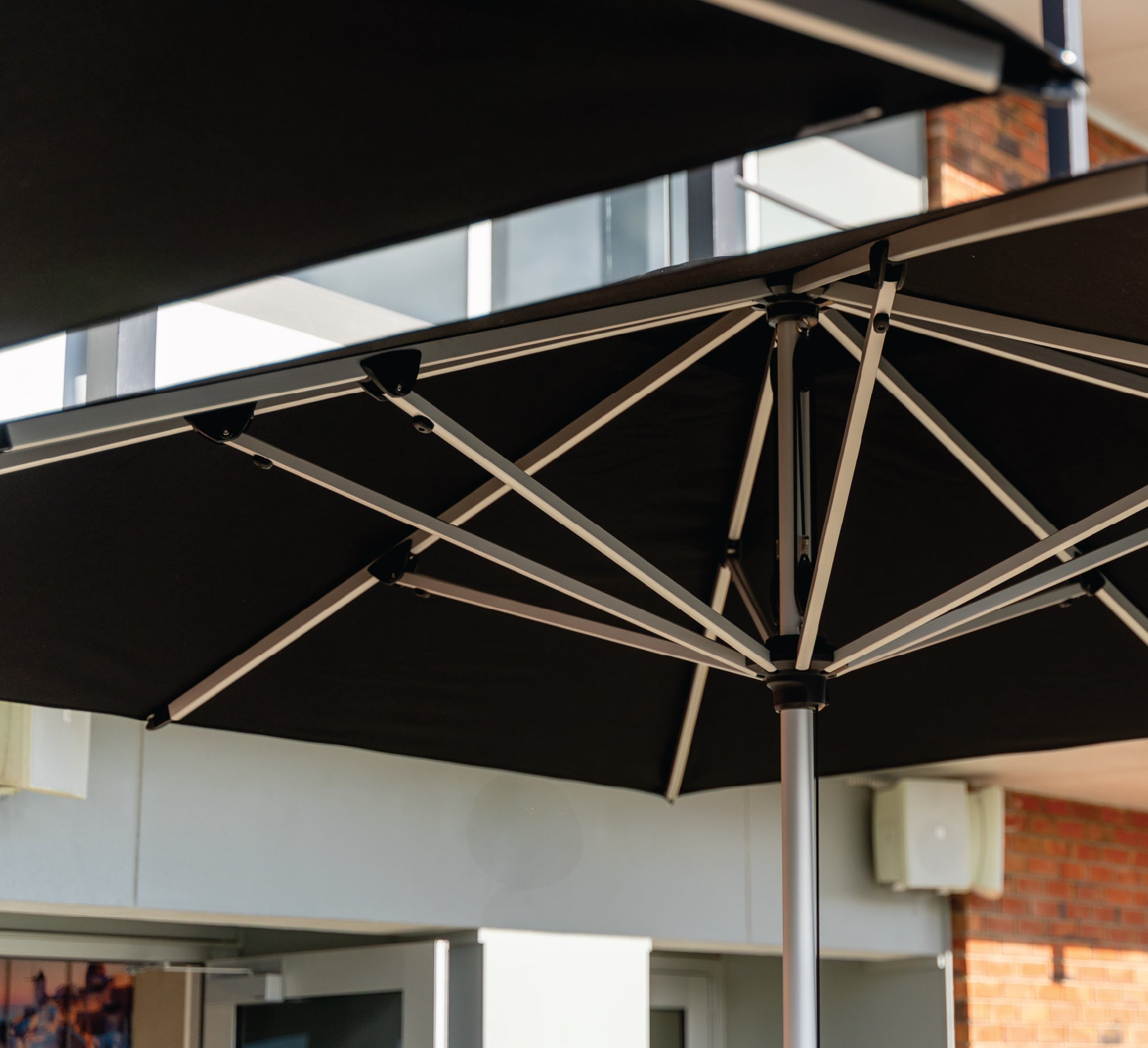 Black outdoor umbrella with metal frame against a building background