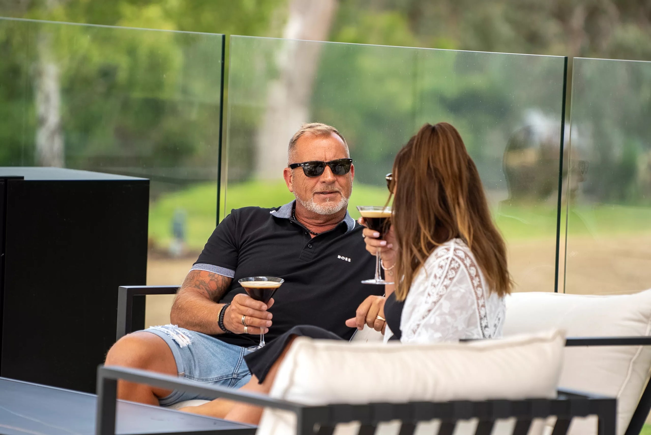 Two people sitting outdoors, enjoying drinks and conversation.